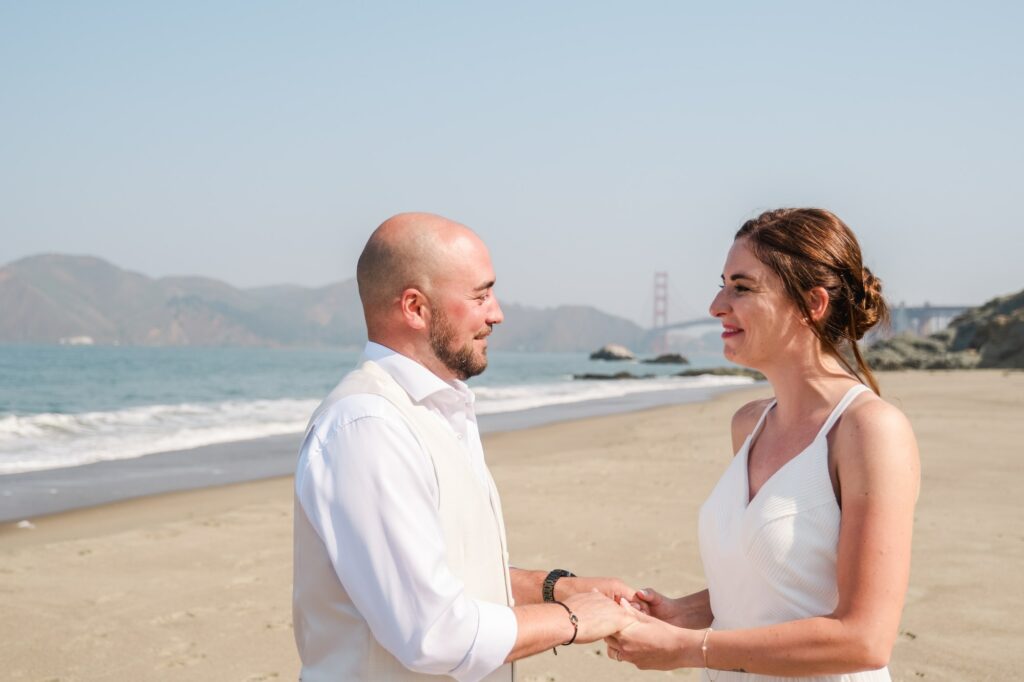 Couple se tenant les mains pendant leur cérémonie de mariage elopement sur une plage de San Francisco