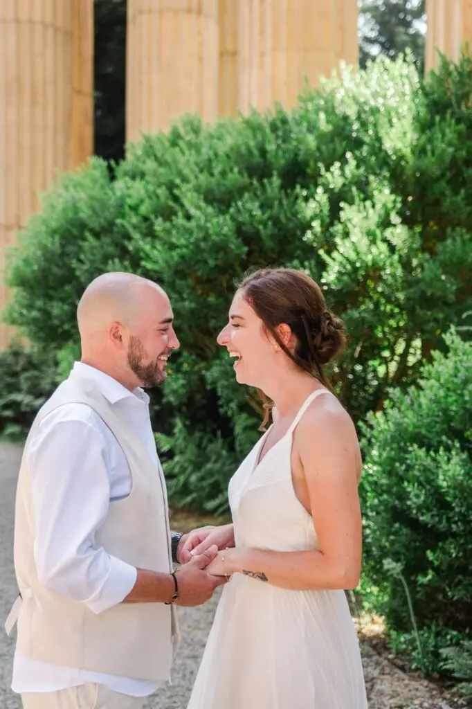 Couple de mariés se tenant les mains et riant au Palace of Fine Arts à San Francisco pendant leur elopement