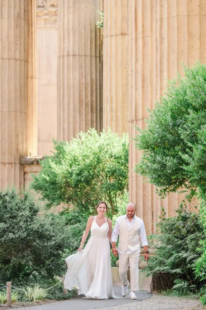 Couple de mariés marchant main dans la main au Palace of Fine Arts à San Francisco photographié par Julien Boyer