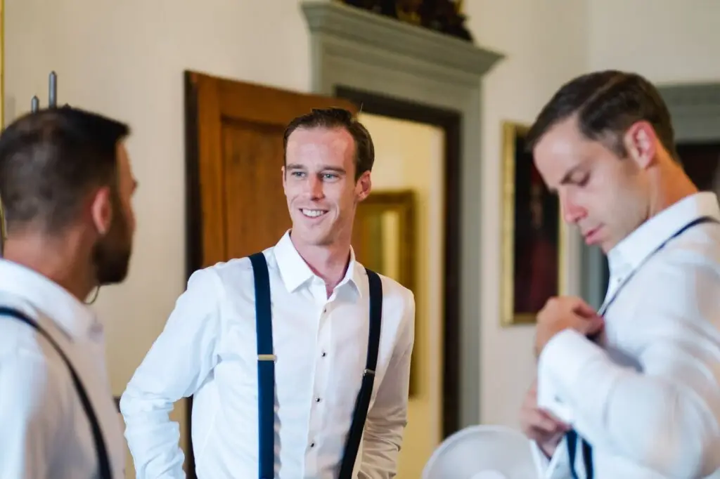 Témoins du marié portant des bretelles bleues pendant les préparatifs d’un mariage à la Villa Vistarenni en Toscane, ambiance élégante et détendue.