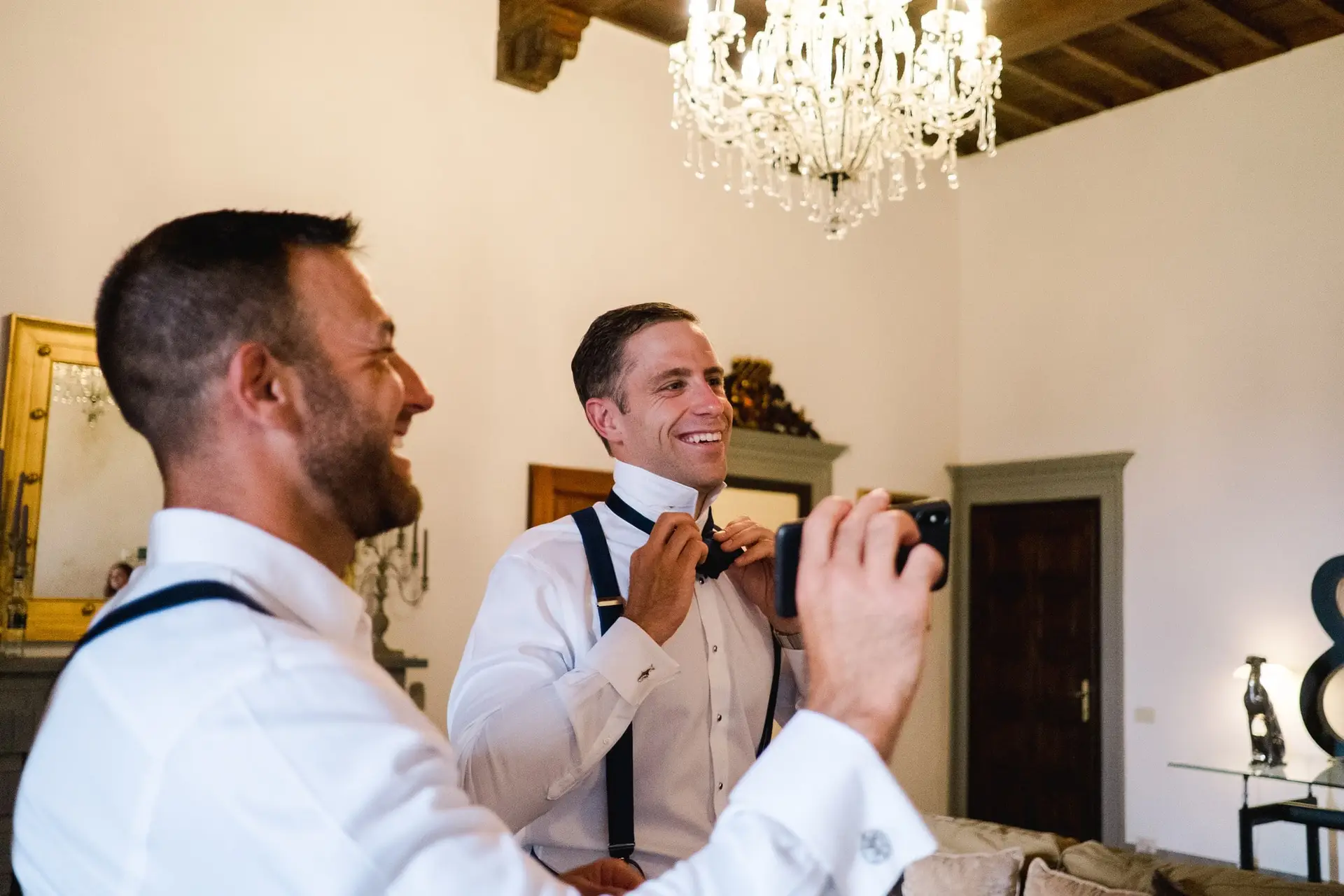 Marié ajustant son nœud papillon devant un miroir lors des préparatifs dans une villa en Toscane, ambiance élégante et naturelle.