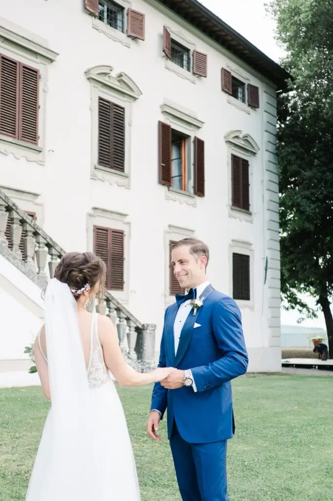 Les mariés se tenant la main devant la Villa Vistarenni en Toscane, photographie de mariage de destination réalisée par Julien Boyer.