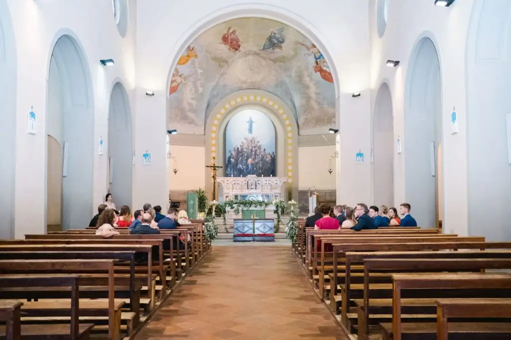 Vue d’ensemble de l’intérieur d’une église en Toscane avant la cérémonie de mariage, bancs en bois et décoration florale élégante.