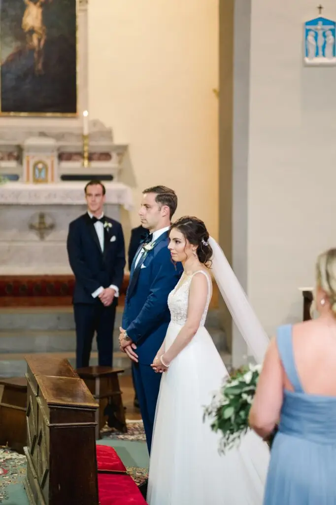 Les mariés échangent un regard complice pendant la cérémonie de mariage dans une église en Toscane, photographie naturelle et émotive.
