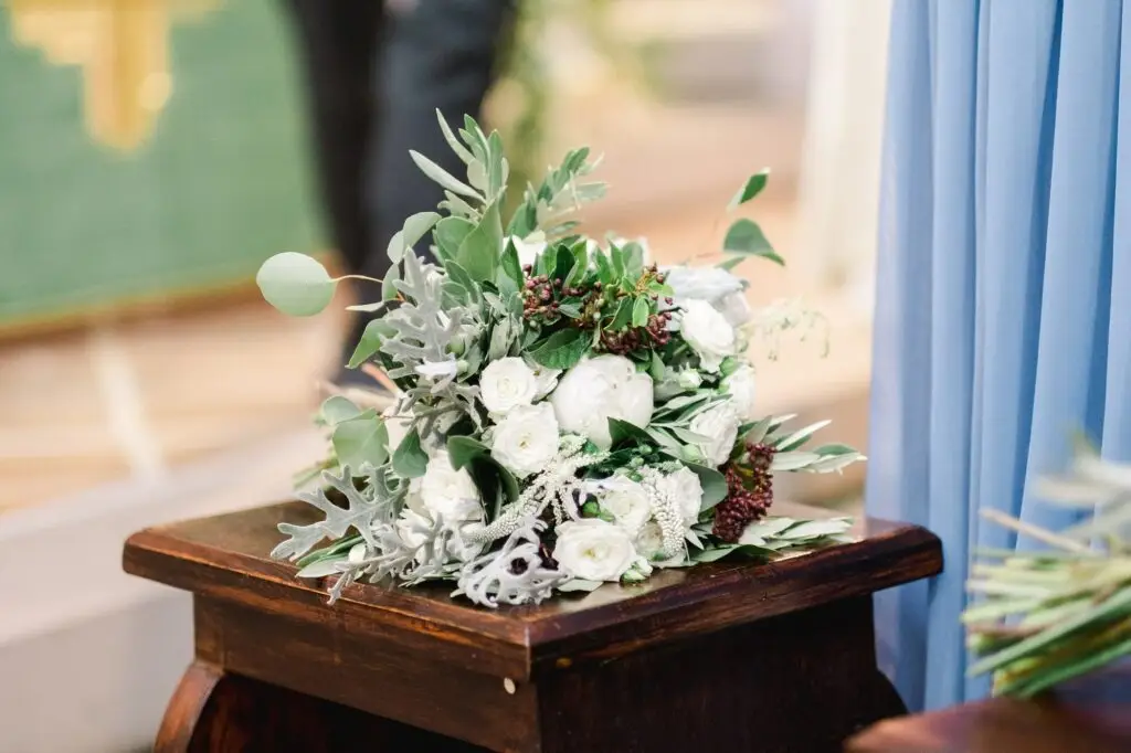 Bouquet de la mariée composé de fleurs blanches et feuillages posé pendant la cérémonie de mariage en Toscane, détail élégant et naturel.