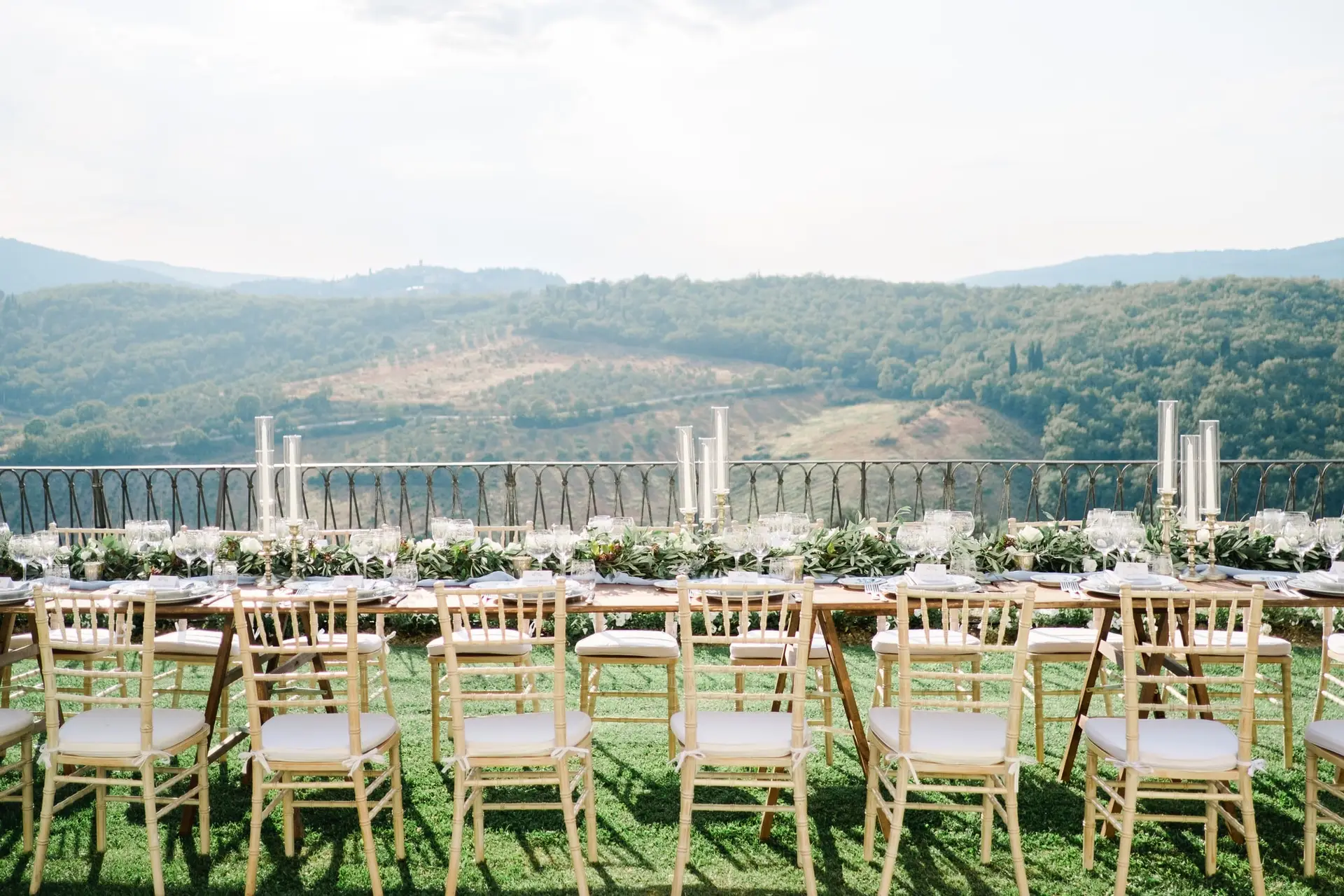 Table de réception dressée en extérieur avec vue panoramique sur les collines de Toscane, décoration raffinée pour un mariage de destination.
