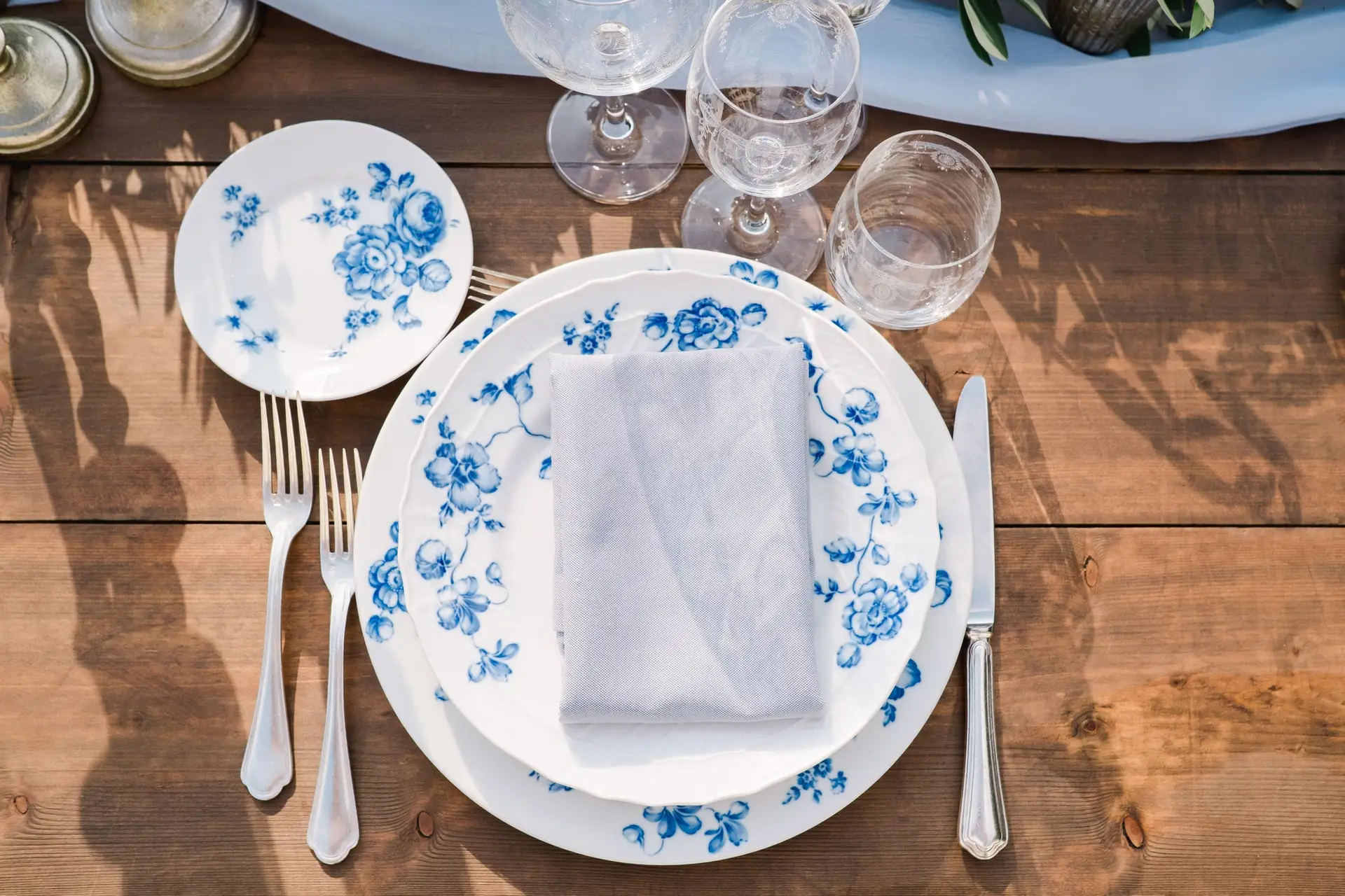 Table de mariage dressée en extérieur avec guirlande végétale et bougies, offrant une vue panoramique sur la Toscane.