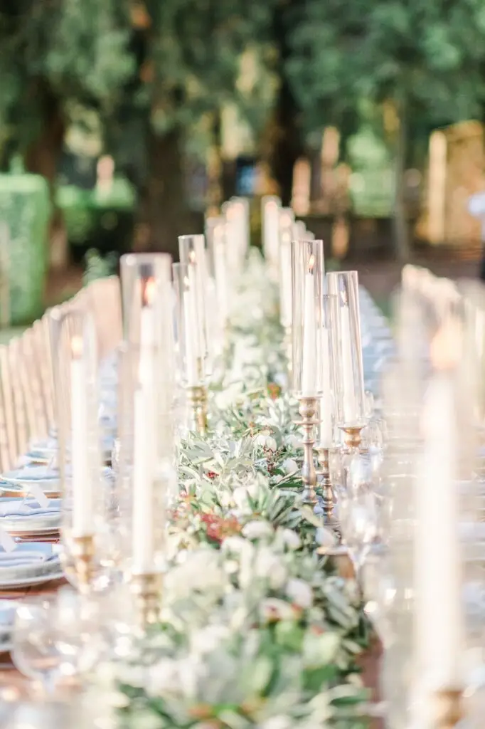 Gros plan sur des verres gravés et une décoration florale délicate lors d’un mariage de destination en Toscane.