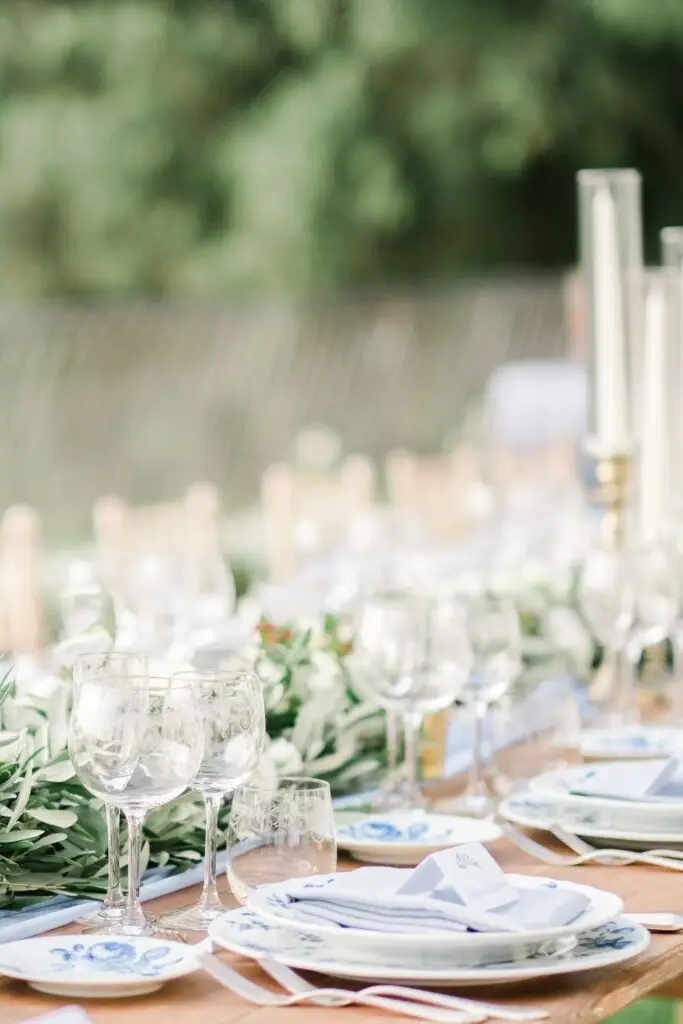 Verres, assiettes et composition florale élégante sur une table de réception en Toscane, photographie de mariage réalisée par Julien Boyer.