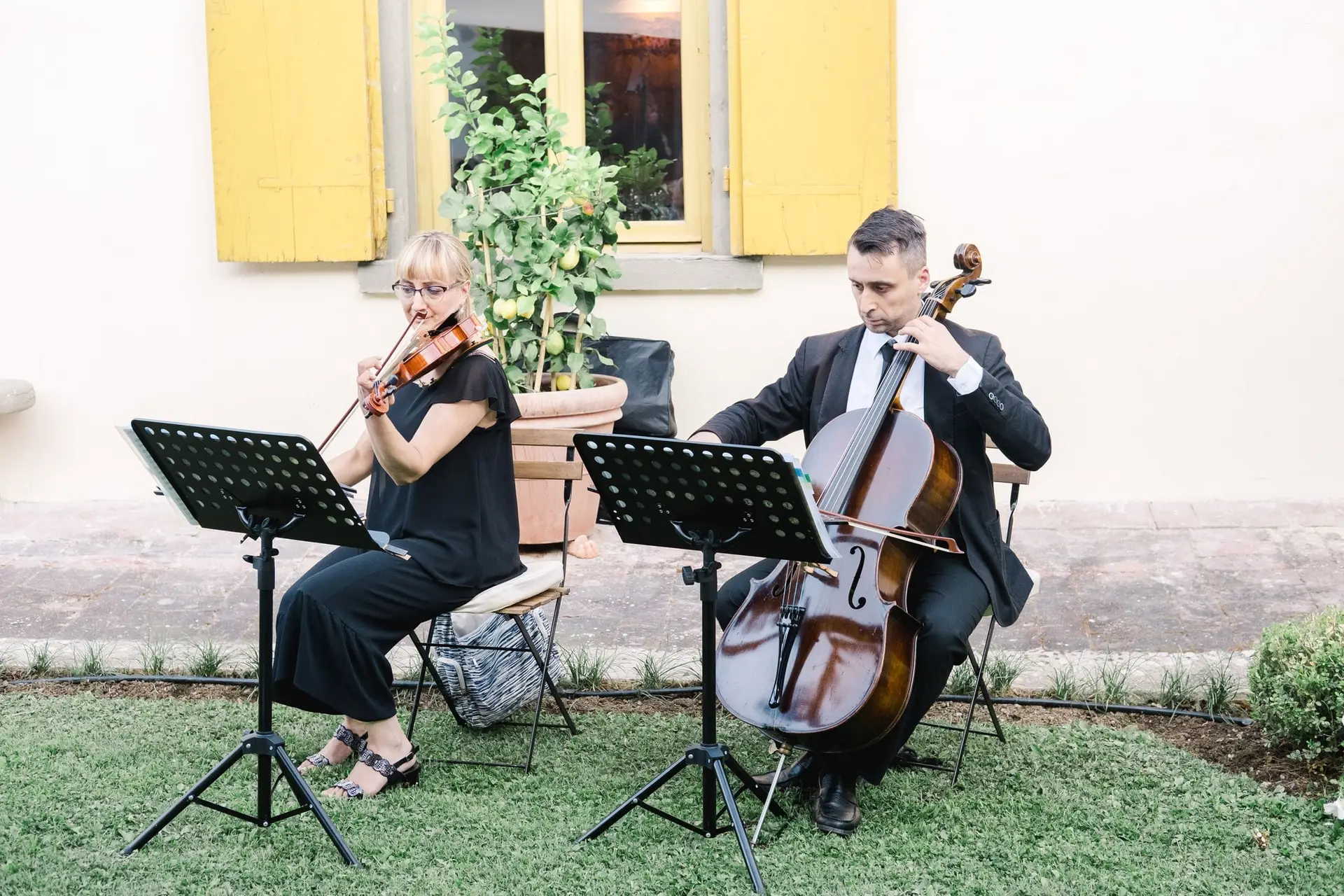 Duo de musiciens jouant du violon et du violoncelle lors du cocktail d’un mariage de destination en Toscane, ambiance raffinée en extérieur.