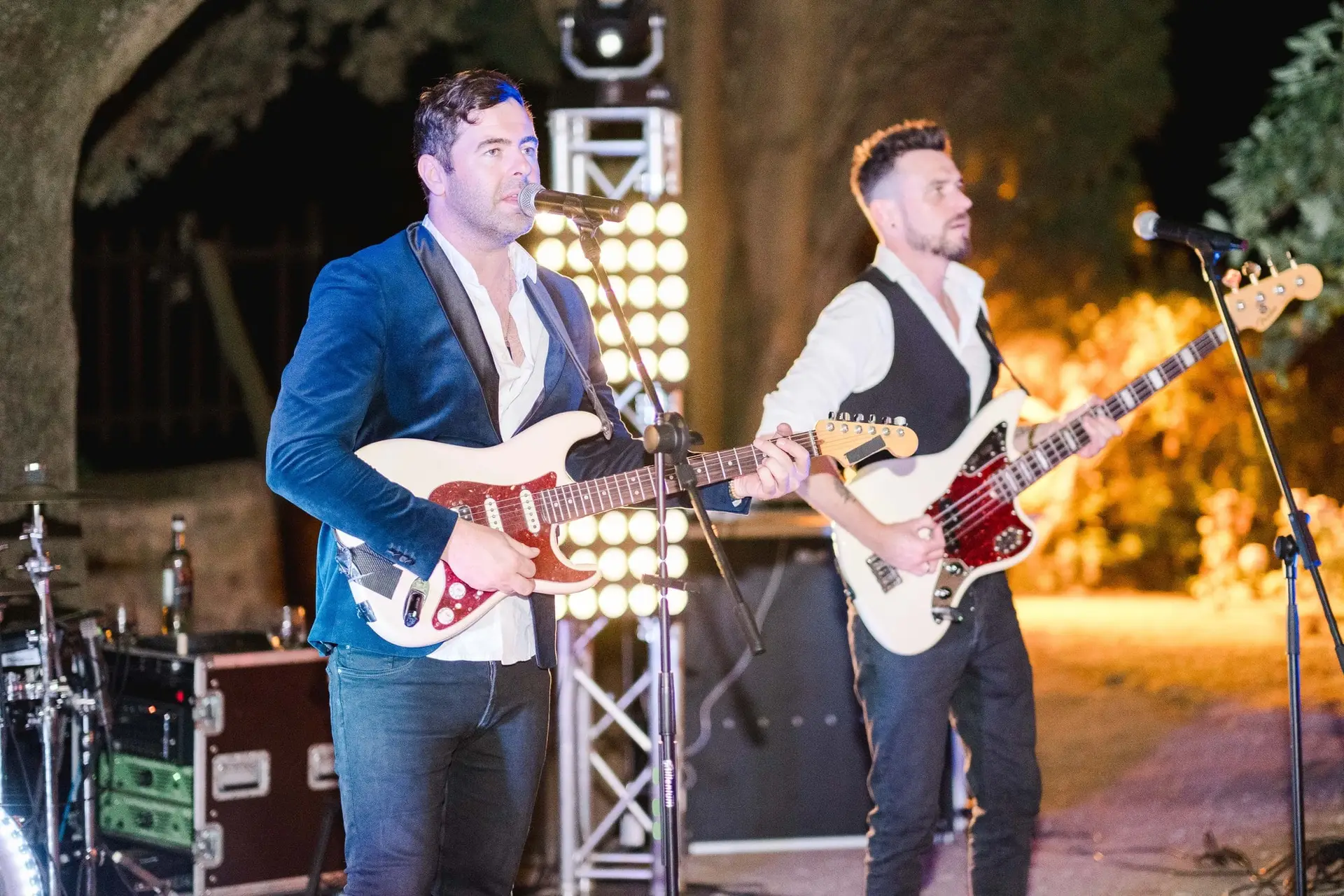 Groupe de musique live animant la soirée de mariage en Toscane, musiciens sur scène en plein air à la Villa Vistarenni, photographie de destination par Julien Boyer.