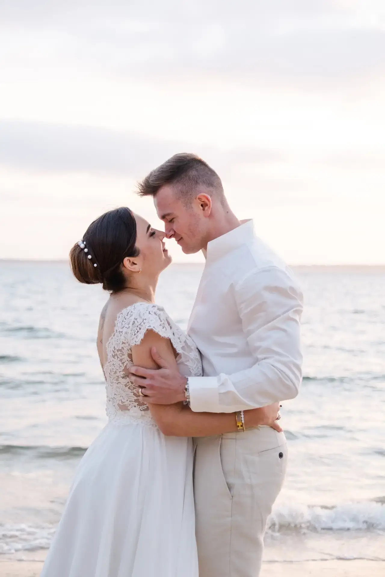 Couple de mariés enlacés sur une plage du Bassin d’Arcachon au coucher du soleil, moment tendre photographié par Julien Boyer.